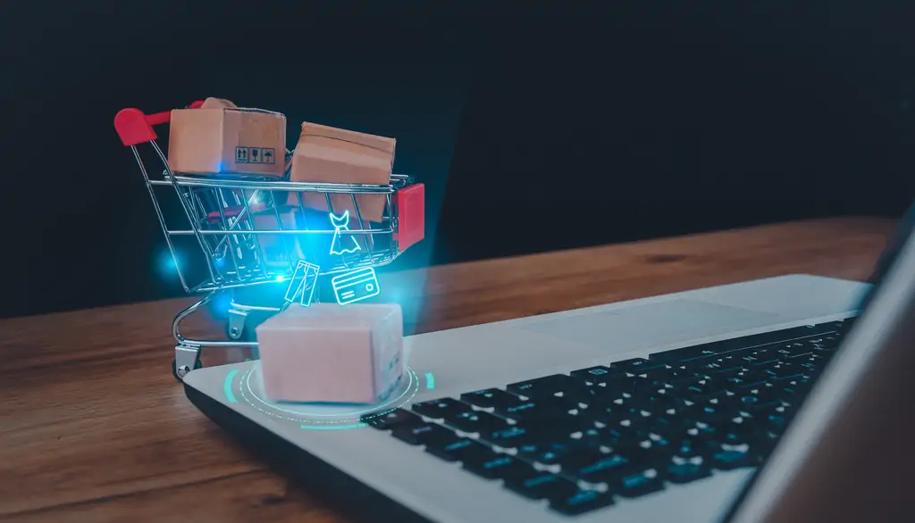 online shopping delivery service concept brown paper boxes shopping cart with laptop keyboard wood table office background customer order things from retailer sites via internet